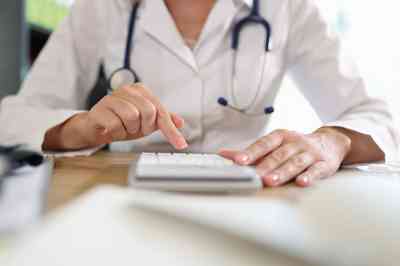 Ärztin arbeitet auf Taschenrechner im Büro